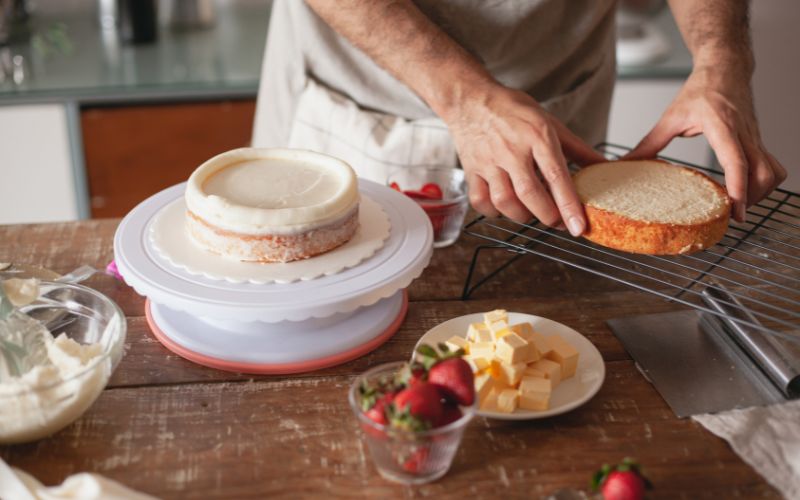 at home Baker building layers of cake on a table