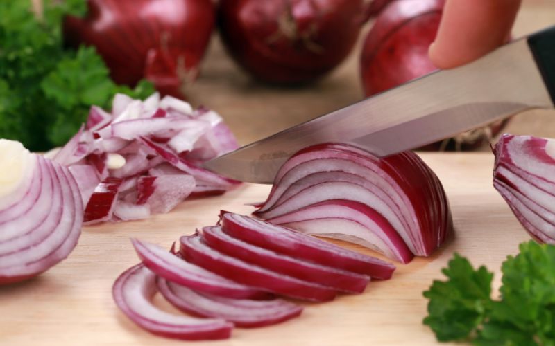 Slicing a red onion with the grain of the onion. 