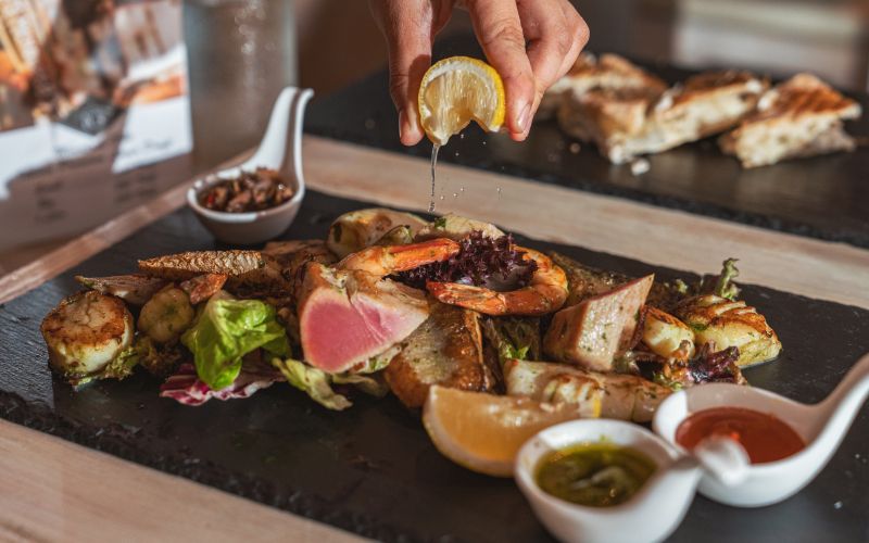 Adding lemon to finish a seafood dish