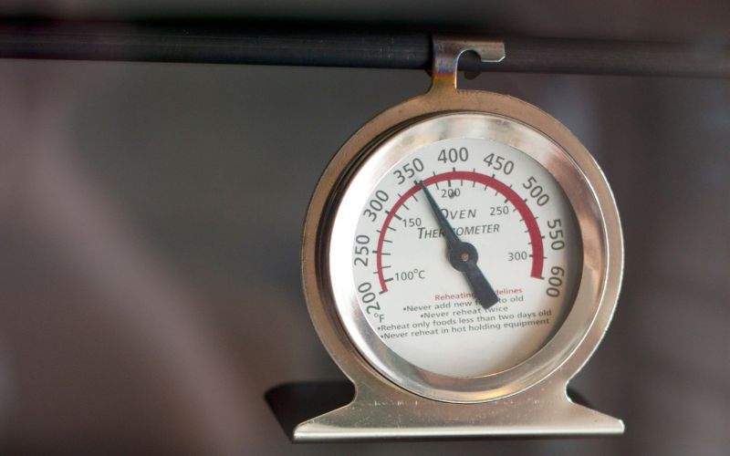 Oven thermometer hanging in an oven.