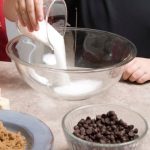 Pouring Sugar into a bowl , making chocolate chip cookies