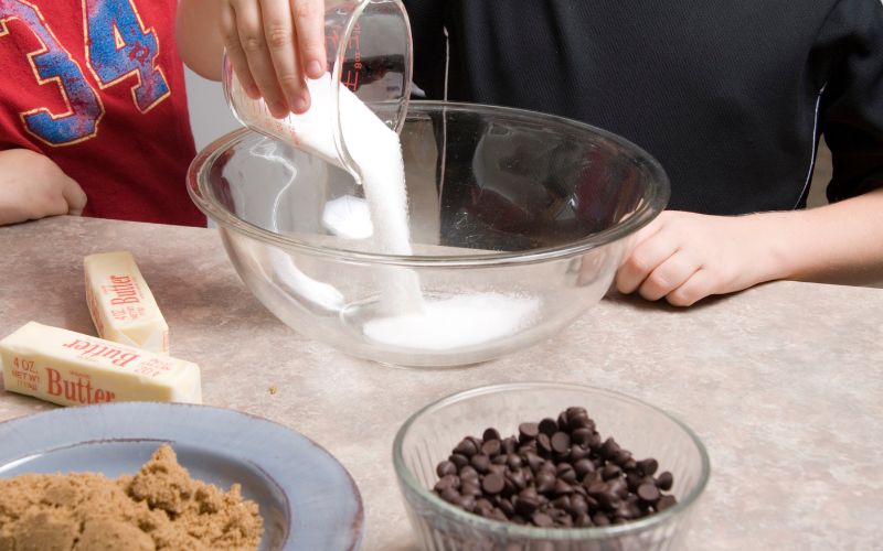 Pouring Sugar into a bowl , making chocolate chip cookies