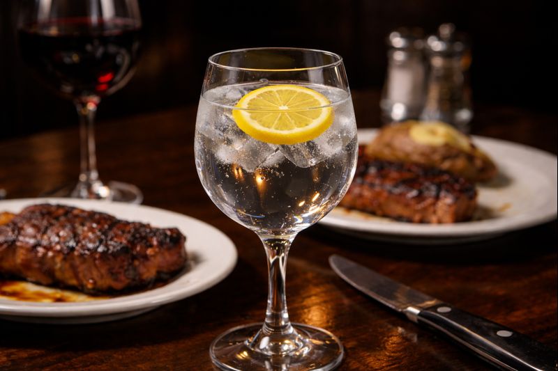 Water in a glass, steaks on the table at a steak house.